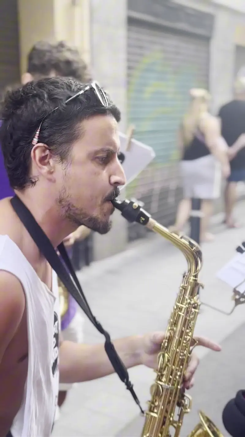 Saxofonista de Tirant Lo Band davant d'un grafit