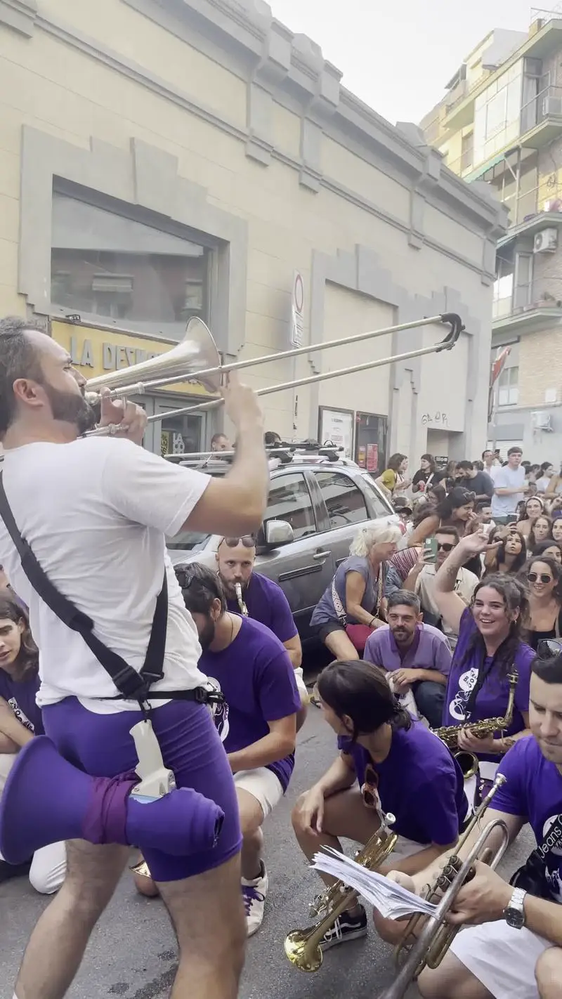 Trombonista tocant enmig del públic assegut al carrer